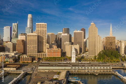 Aerial daytime view of the Embarcadero of the San Francisco, California, skyline. Ferry building in the foreground, ample copy space in blue sky. Morning light.