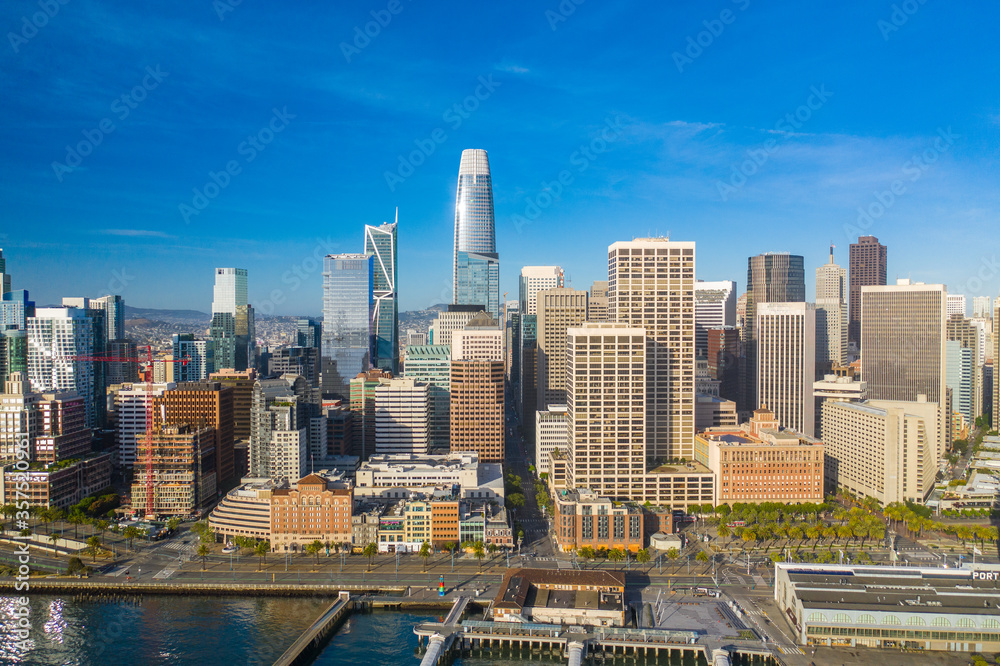 Naklejka premium Aerial daytime view of the Embarcadero of the San Francisco, California, skyline. Ferry building in the foreground, ample copy space in blue sky. Morning light.