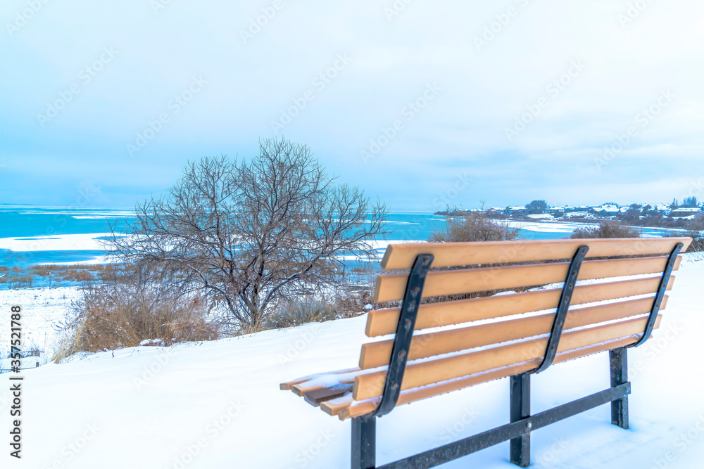 Magnificent scenery at the Utah Lake with an empty bench on the snowy terrain