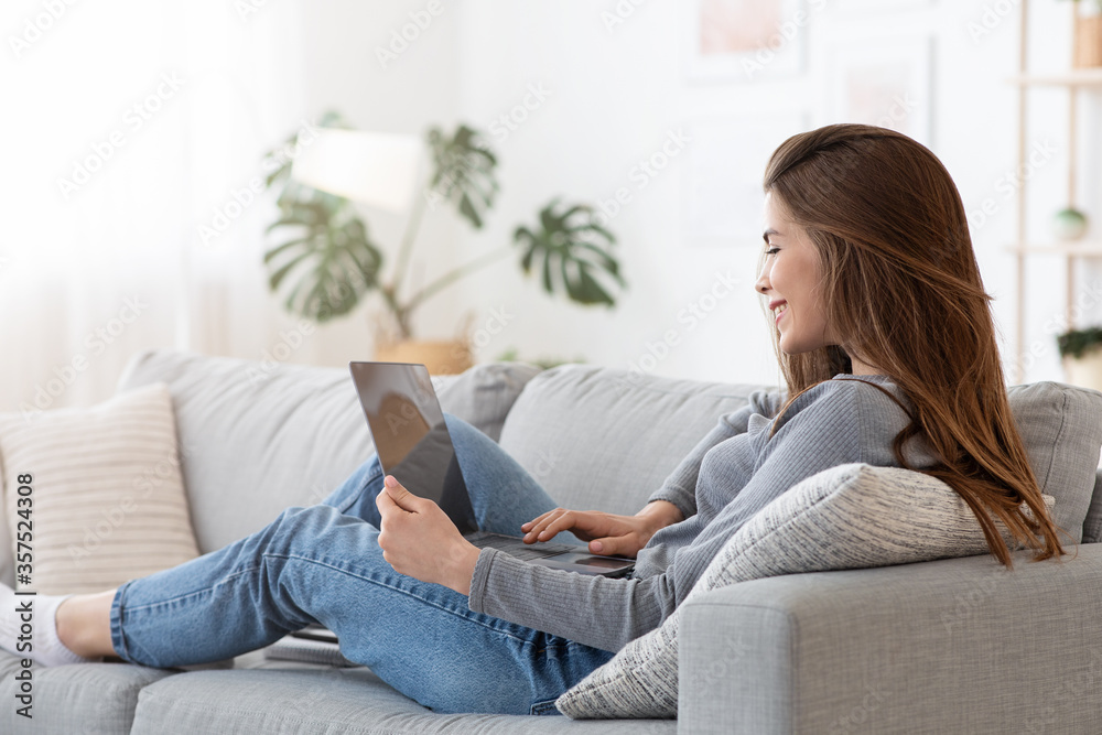 Relaxed girl spending weekend with laptop on couch Relaxed girl spending weekend with laptop on couch