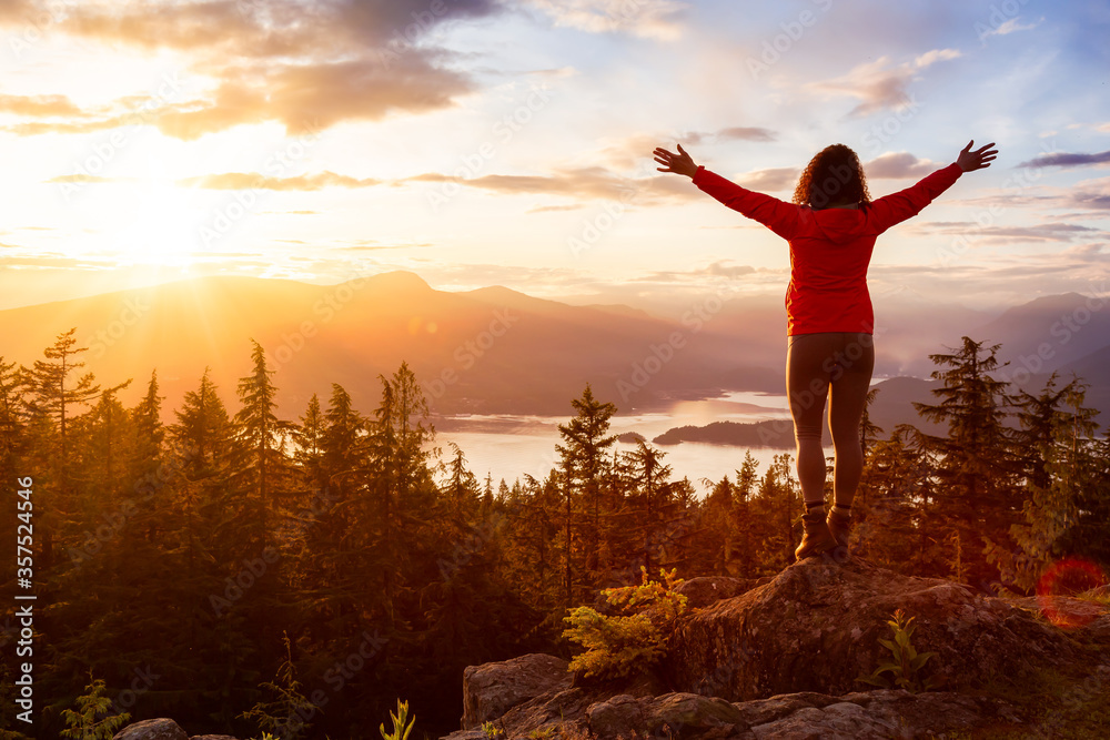 Adventure Girl on top of a Mountain with Canadian Nature Landscape in the Background during colorful sunset. Taken on Bowen Island, near Vancouver, British Columbia, Canada. Adventure Girl on top of a Mountain with Canadian Nature Landscape in the Background during colorful sunset. Taken on Bowen Island, near Vancouver, British Columbia, Canada.
