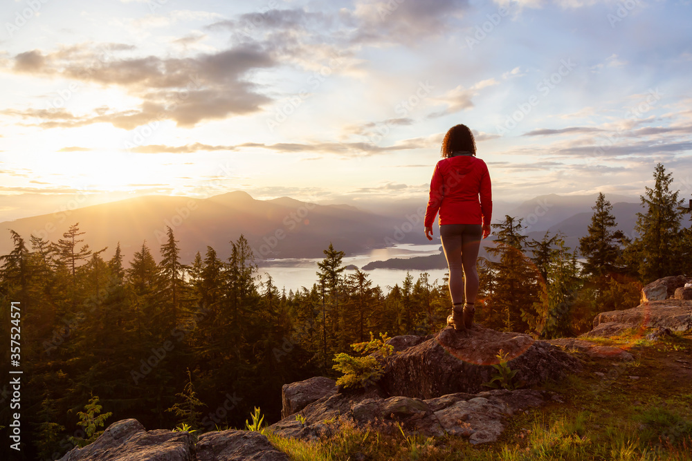 Adventure Girl on top of a Mountain with Canadian Nature Landscape in the Background during colorful sunset. Taken on Bowen Island, near Vancouver, British Columbia, Canada.