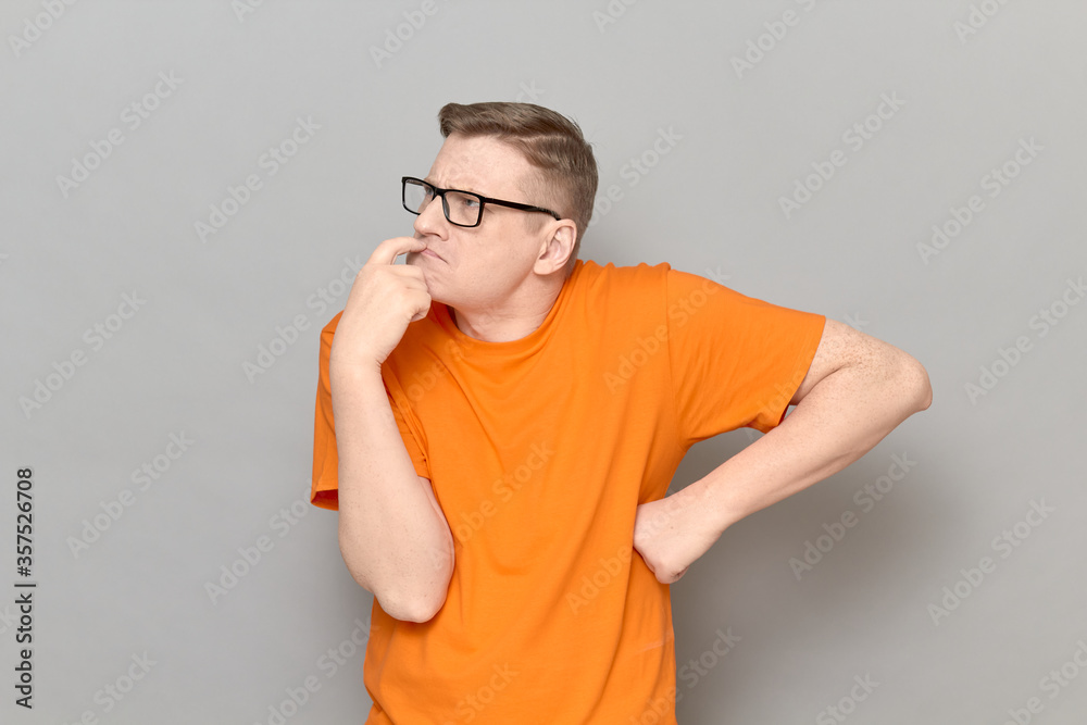 Portrait of funny man touching lips with finger and thinking hard Portrait of funny man touching lips with finger and thinking hard