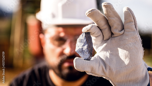Fotografie miner man holding a silver stone, point focus