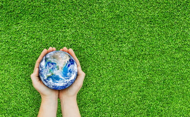 Ecology and Environment Concept : Top view of Hand holding blue planet earth over green grass. (Elements of this image furnished by NASA.)