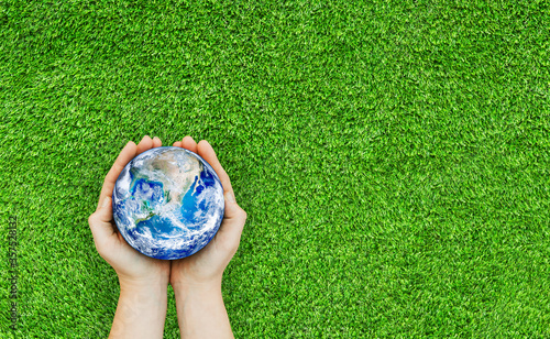 Ecology and Environment Concept : Top view of Hand holding blue planet earth over green grass. (Elements of this image furnished by NASA.)