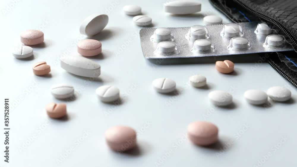 Top view of white pills spilling on white desk Top view of white pills spilling on white desk