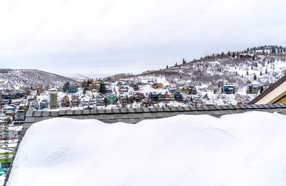 Gray snowy roof against colorful homes on frosted hill in Park City Utah