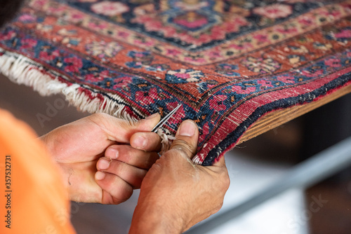 traditional hand sewing fixing with clippers old vintage antique persian carpet up close