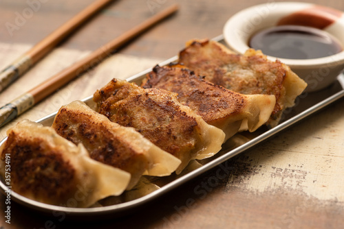 gyoza on silver plate wooden table chopsticks and soy sauce