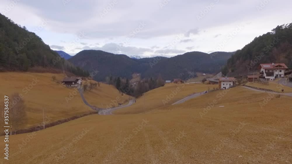 Aerial: Drone flying forward towards car on road in village near mountains against sky - Dolomites, Italy Aerial: Drone flying forward towards car on road in village near mountains against sky - Dolomites, Italy