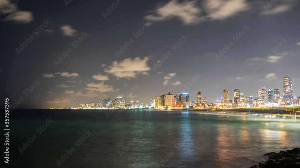 Seascape and skyscrapers on background at night in Tel Aviv, Israel.