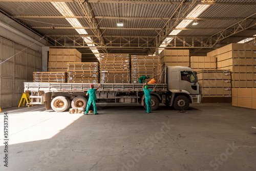 men loading truck on factory floor shed with mdf pine wood sheets