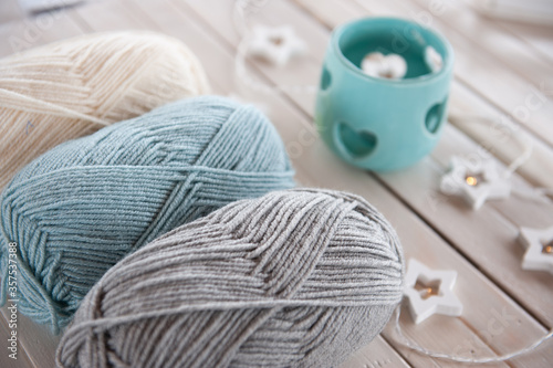 Wool yarn milky, gray, mint color lie on a light wooden table