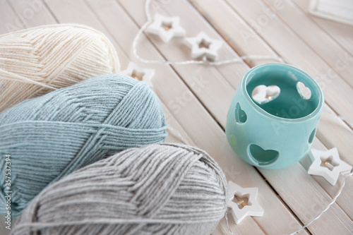 Wool yarn milky, gray, mint color lie on a light wooden table