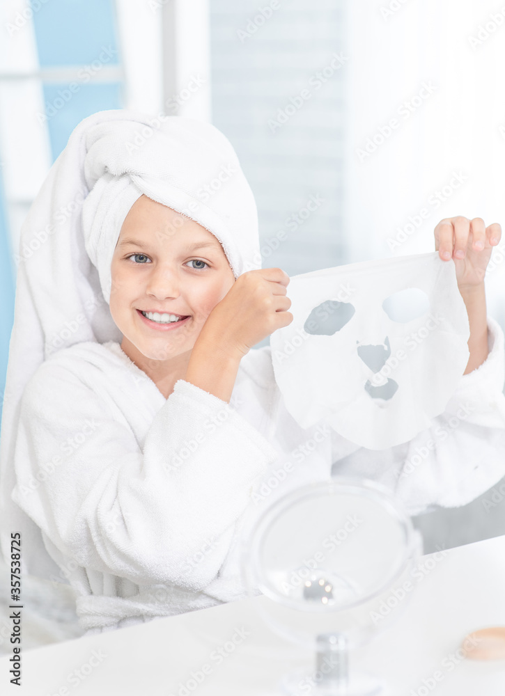 Smiling girl wearing towel on her head holds mask for face skin Smiling girl wearing towel on her head holds mask for face skin