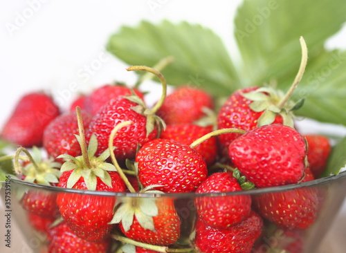 Strawberries in a glass vase on a light gray background. Copy space. Summer berry theme.