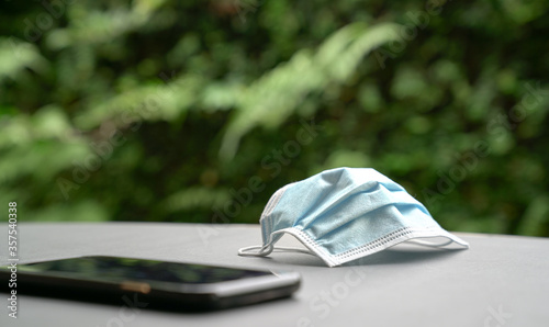 Medical face mask and cellphone on table.