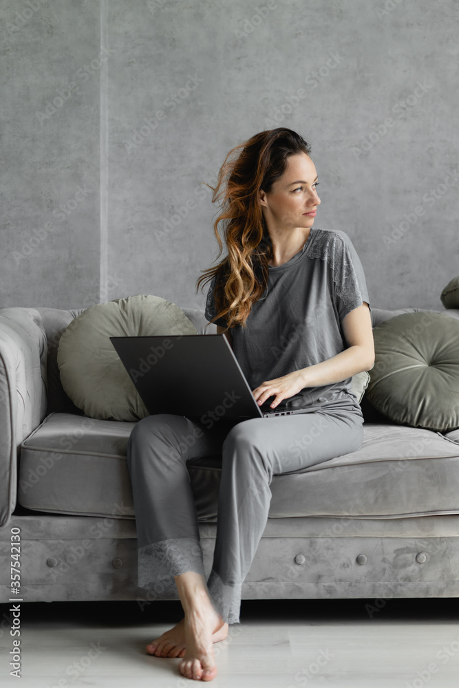 Modern business lady working from home sitting on the couch with a laptop on her lap. Conference with business partners from the apartments. Webcam chat and weekend conferencing. Modern business lady working from home sitting on the couch with a laptop on her lap. Conference with business partners from the apartments. Webcam chat and weekend conferencing.