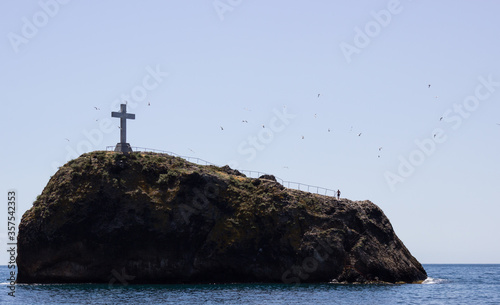 Crimea, Sevastopol, Gergiev rock with a cross in the middle of the sea, a lonely man on it and many gulls