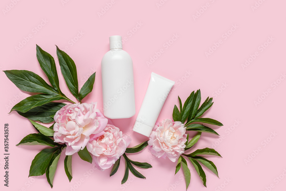 Cosmetic bottle containers with peony flowers on a pink background. Blank label for branding mock-up, Copy space.