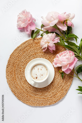 Cup of coffee and peony flowers on the table. Top view. Flat lay.