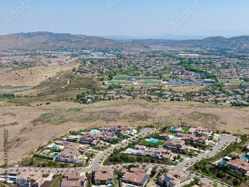 Aerial view of high class neighborhood with residential mansions and swimming pools in dry grass valley during hot summer. San Diego, California, USA.
