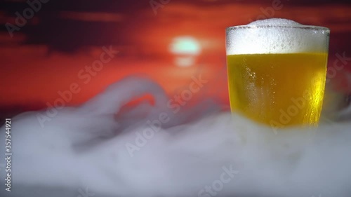 Glass of beer on a beach at sunset.