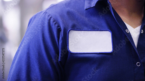 Blue uniform shirt with empty name white patch, unrecognizable worker or employee Identification.