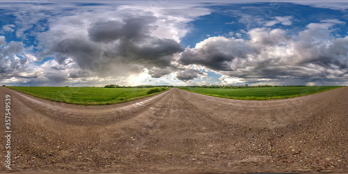 full seamless spherical hdri panorama 360 degrees angle view on wet gravel road among fields in spring day with storm clouds after rain in equirectangular projection, ready for VR AR content