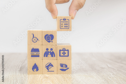 Close-up hand choose cube wooden toy blocks with insurance icon for safety family insurance.