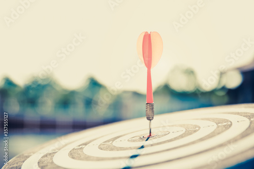 Bullseye or dart board has dart arrow throw hitting the center of a shooting target for business targeting and winning goals business concepts.