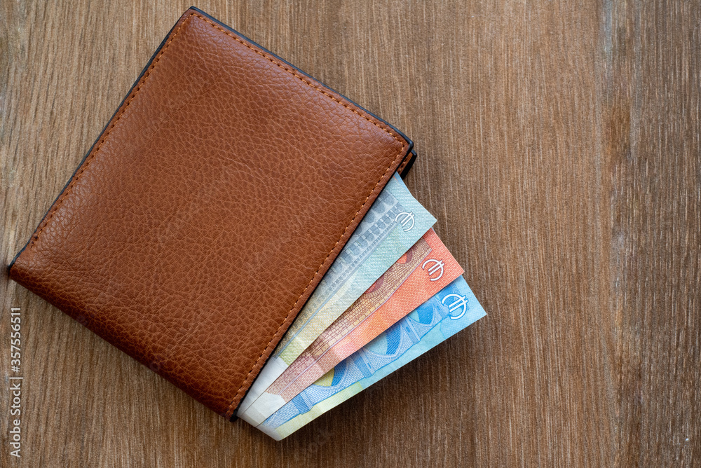New leather wallet with euro money on a wooden background