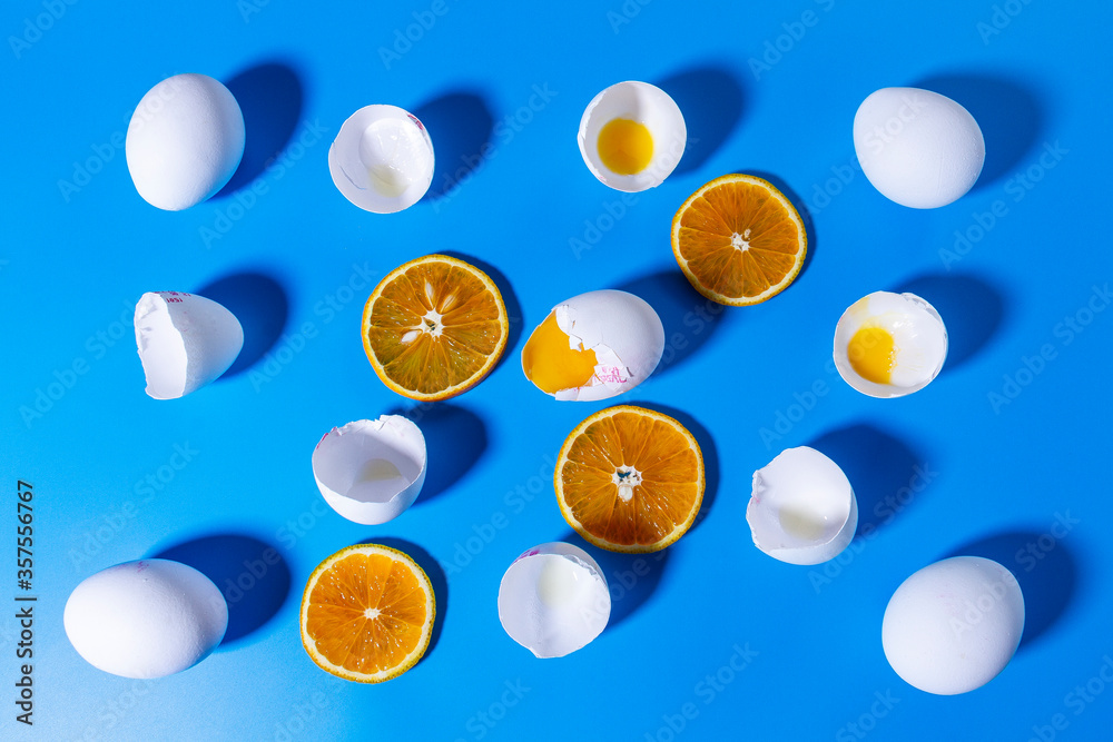 Background. Texture. Broken eggs, eggs, eggshell and sliced ​​oranges on a blue background.