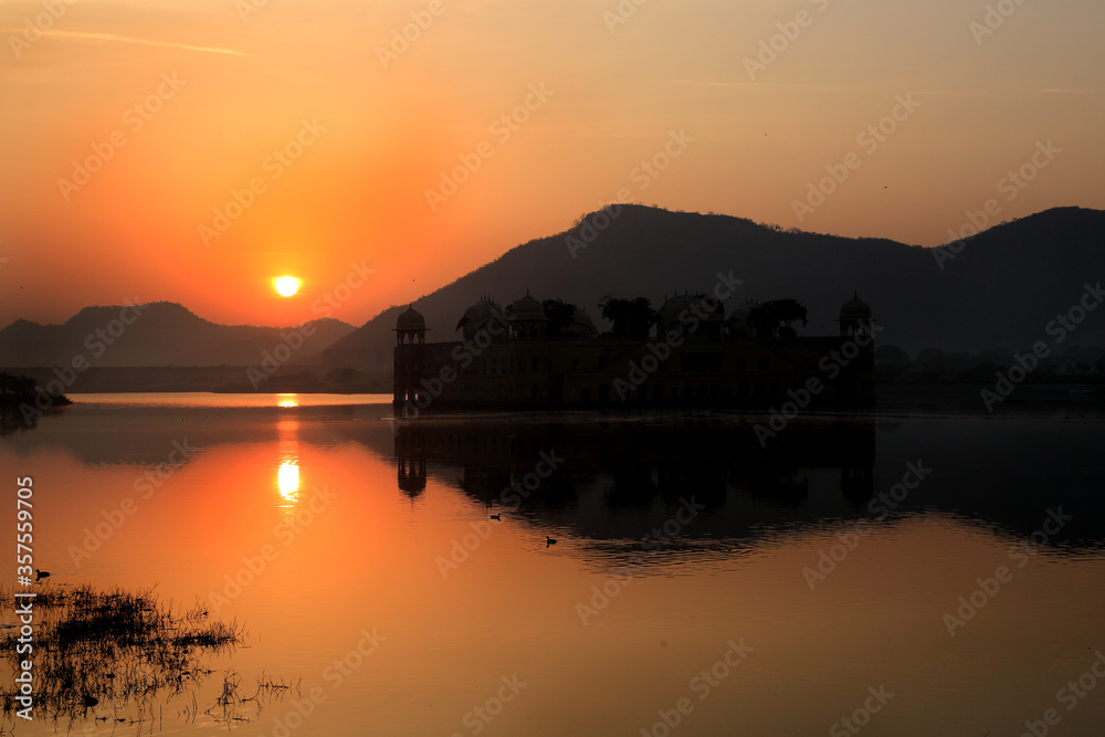 A view of Sunrise.Sun rising from behind the Hills and showing its reflection in the water of the lake. A view of Sunrise.Sun rising from behind the Hills and showing its reflection in the water of the lake.