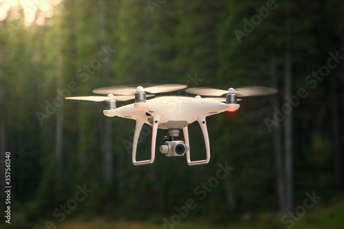 Drone flying in nature. Green trees in background. Low angle, shallow depth of field