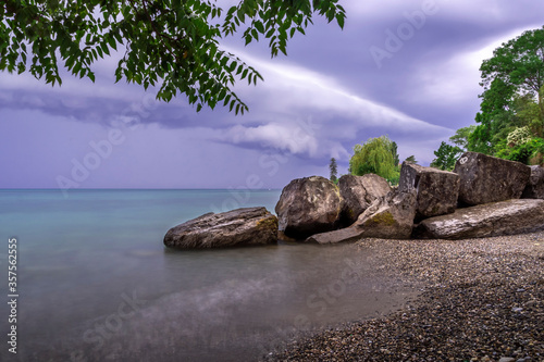 Nuages d'orage en bord de plage et devant des rochers sur le lac Léman