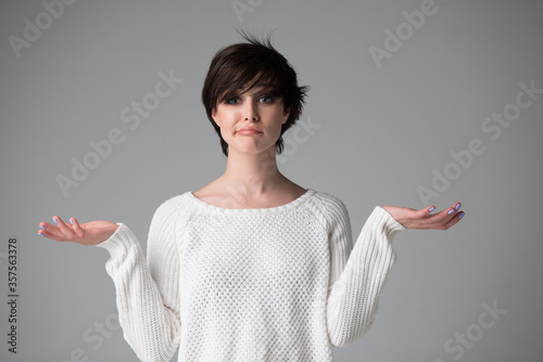 Beautiful young woman with nothing to do gesture, studio shot over gray background. Pretty girl with expressive facial expressions using language of body to say apologies, regret, failure, fail