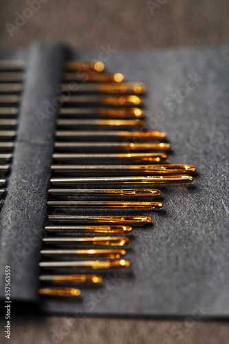 Sewing needles on a black background in a row.