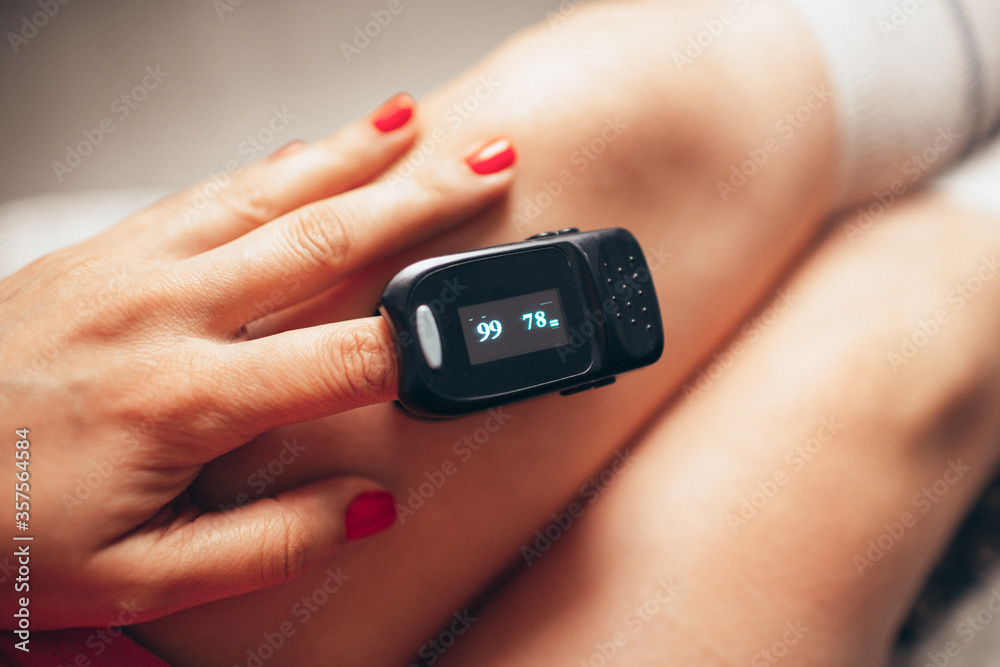 Pulse oximeter on woman's left hand. Oxygen level and pulse measuring. Pulse oximeter on woman's left hand. Oxygen level and pulse measuring.