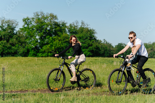 Family having great time, riding in a countryside, along trees and fields