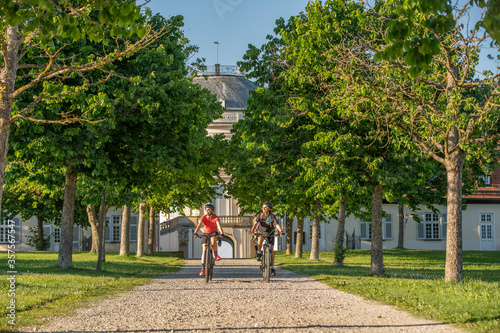 Grandmother and granddaughter riding their mountain bikes and having fun on a sunny afternoon in in front of Soliude castle near the city of Stuttgart, Baden-Wuerttemberg, Germany