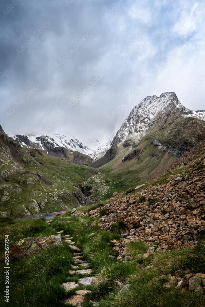 Montaña nevada con camino de piedras en primer plano. Ibón de Llauset pico Culebras, pirineo aragonés