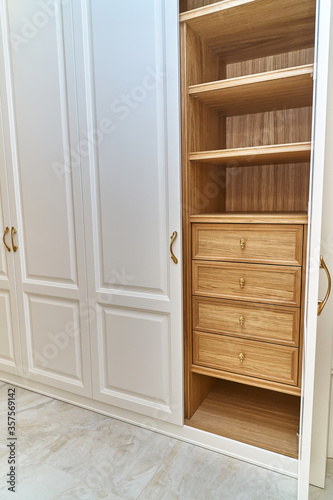 White wardrobe with wooden drawers and shelves. Wooden filling of wardrobe