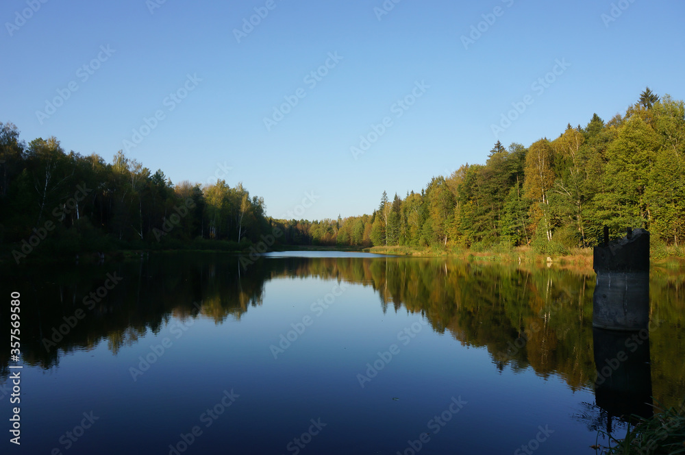 Forest lake at the end of September. Peaceful contemplation. Autumn in the Moscow region, Russia.