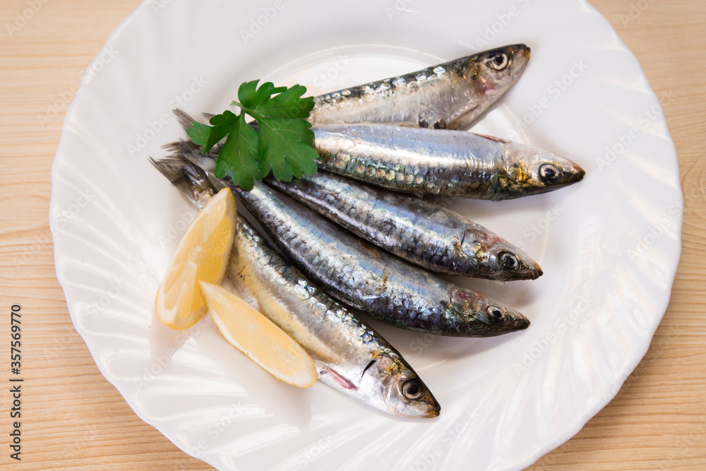 plate of fresh sardines with parsley and lemon on the plate plate of fresh sardines with parsley and lemon on the plate