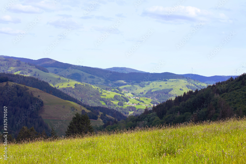 Green hills landscape, view on mountains and valley. Black Forest Mountains, springtime. Hills, fields, meadows and forest. Schwarzwald panorama, rolling landscape. Germany