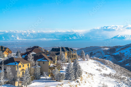 Homes on pristine snowy terrain overlooking valley lake and Wasatch Mountains