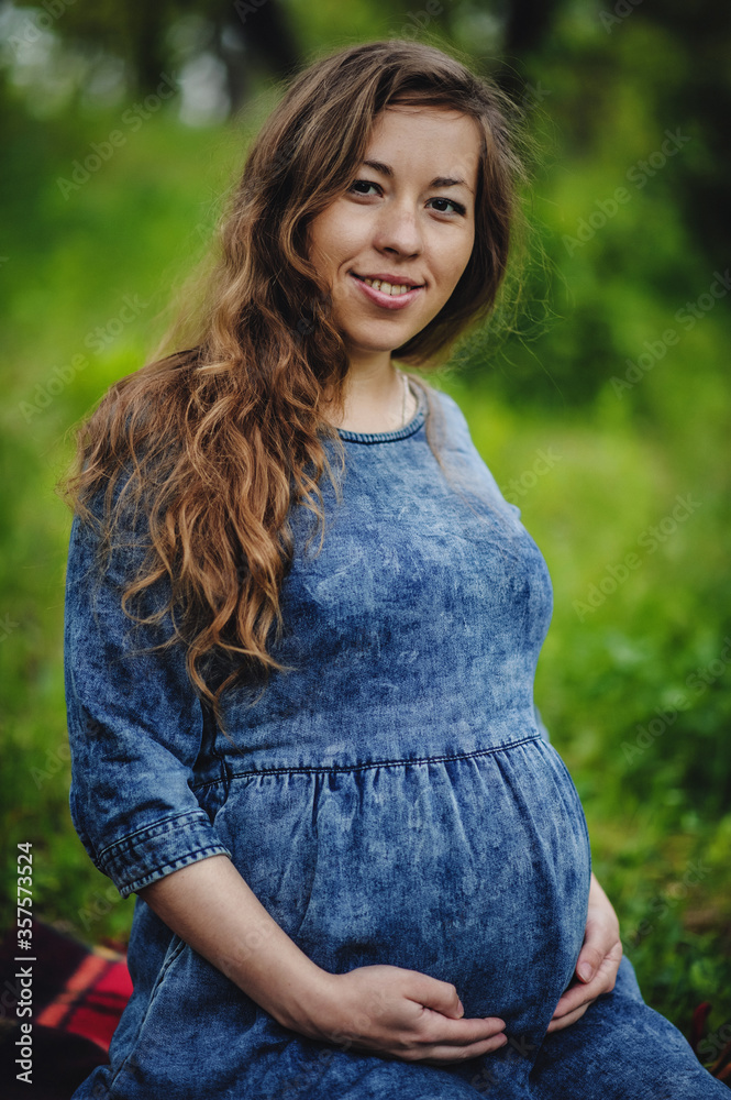 Expectation of the child. Pregnant woman in the park, the meadow covers the round stomach. Close up. Nine months. The concept of motherhood. Happy mama. Expectation of the child. Pregnant woman in the park, the meadow covers the round stomach. Close up. Nine months. The concept of motherhood. Happy mama.