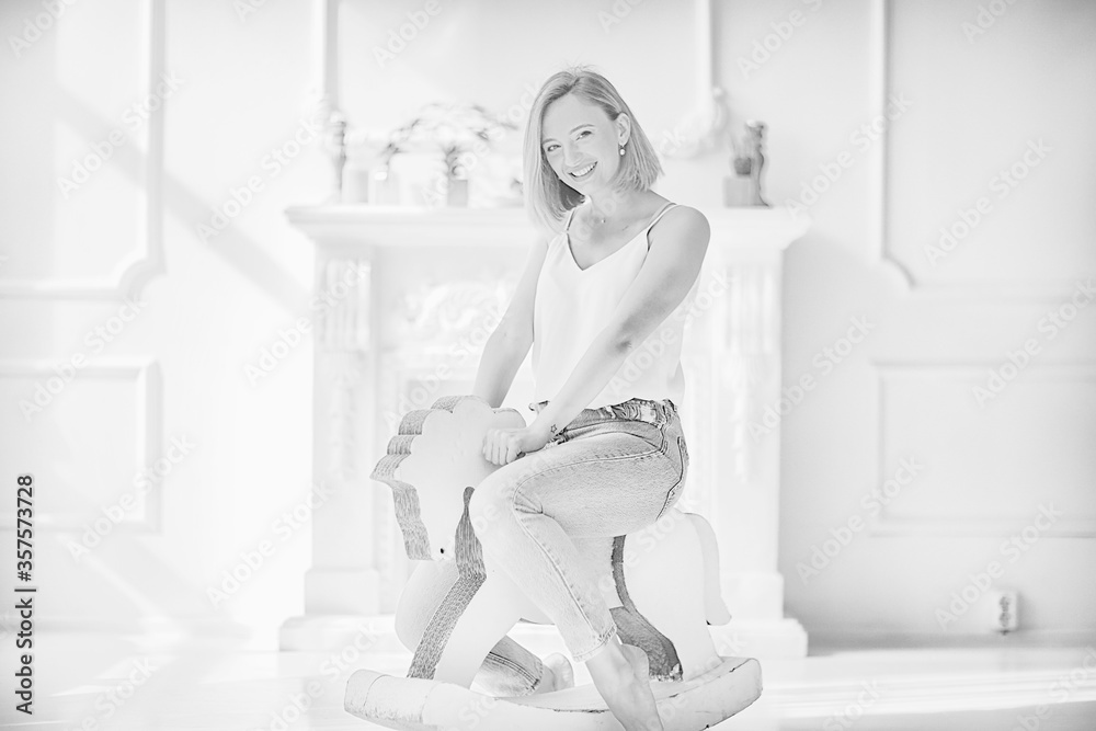 Φωτογραφία young adult girl on a rocking horse / unusual photo of a girl in the studio funn